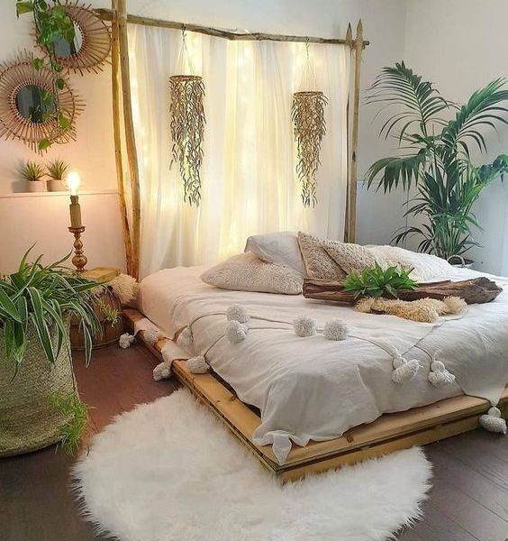 a white bed sitting in a bedroom next to two potted plants on top of a wooden platform