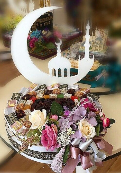 a decorated tray with flowers and sweets on it in front of a mirror that is reflecting the image of a mosque