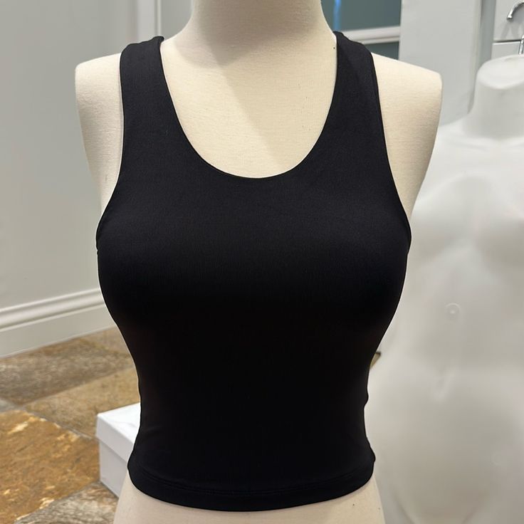 Pullover Style Form Fitting 84% Polyamide, 16% Lycra Black Tank Crop Top With Seamless Construction, Black Seamless Tank Crop Top, Sleeveless Seamless Top For Night Out, Black High Stretch Crew Neck Tank Top, Black Scoop Neck Crop Top With Built-in Bra, Black High Stretch Crop Top Tank Top, Trendy Black Seamless Crop Top, Chic Seamless Workout Tops, Black Cropped Tops With Seamless Construction