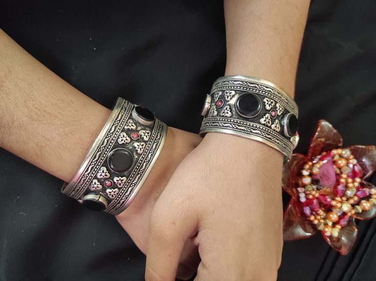 * This traditional craft is embellished with black stones and intricate carved designs, inspired by the true Afghani ornaments. The light in weight, yet exclusive bracelet would add an ethnic touch to your attire. The pick tiny stones are complimenting the tribal style of the hand accessory. You can pair this elegant ornament with any traditional or trendy attire, as per your liking. Note: The product is handmade, so slight change might occur in the actual product. Bohemian Festival Bracelets, Traditional Round Beaded Bracelets For Festival, Bohemian Cuff Bracelet For Ceremonies, Heavy Metal Bracelet For Festival, Heavy Metal Bracelets For Festival, Bohemian Metal Bangle With Intricate Design, Bohemian Metal Cuff Bracelet For Festive Occasions, Traditional Metal Bangle Cuff Bracelet, Silver Bohemian Cuff Bracelet