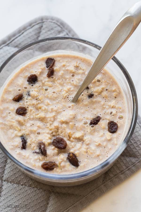 a bowl of oatmeal with raisins and a spoon in it