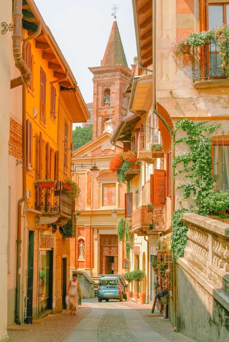 an alley way with cars parked on both sides and flowers hanging from the balconies