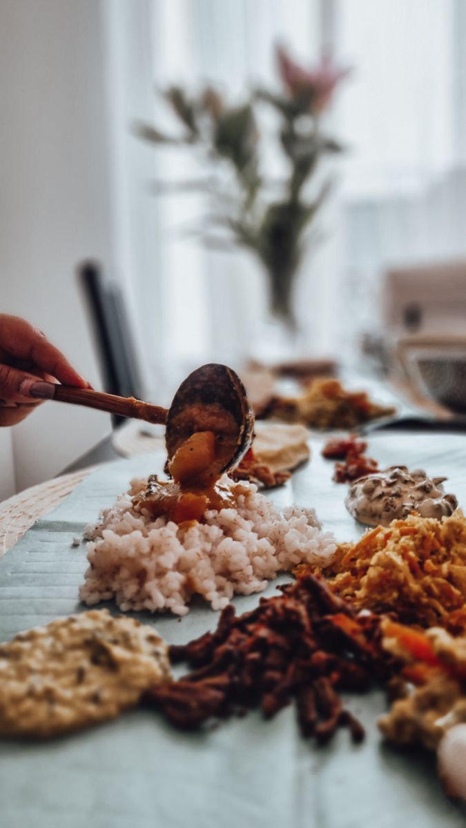 a person scooping food out of a bowl onto a table with other foods on it