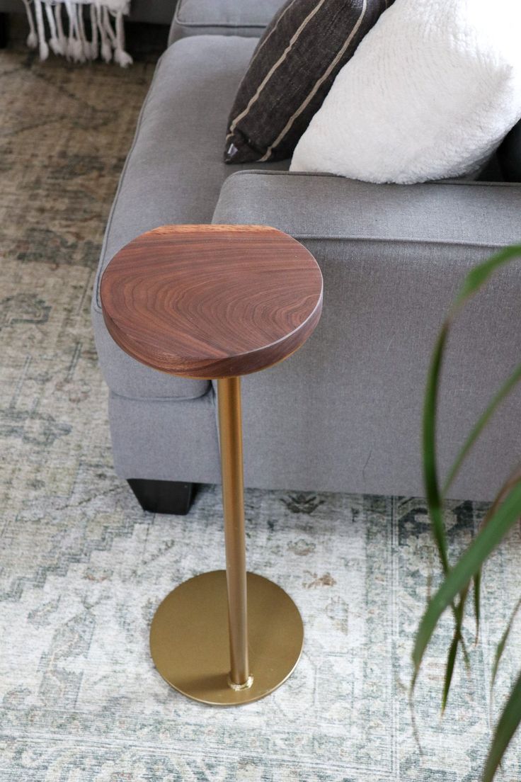 a living room with a gray couch and wooden table in the middle, next to a plant