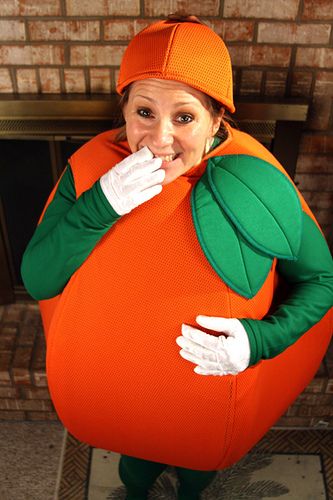 a woman dressed in an orange and green costume poses for the camera with her hands on her mouth