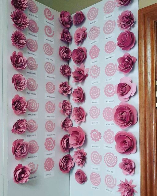 pink paper flowers are arranged on a white wall