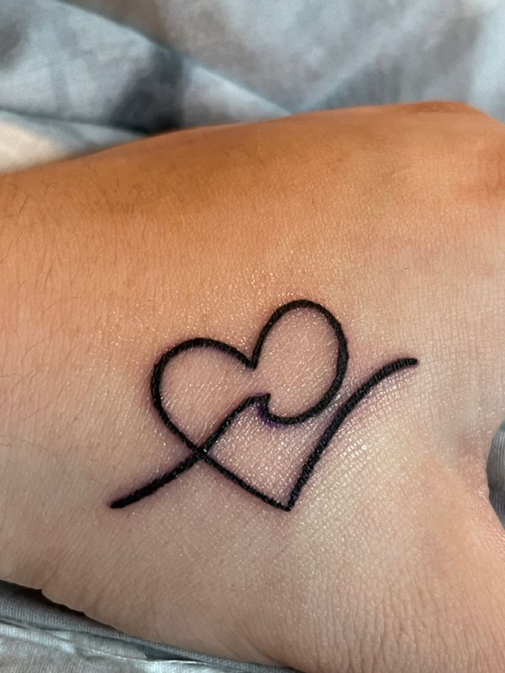 a small tattoo on the wrist of a person with a heart and cross in it