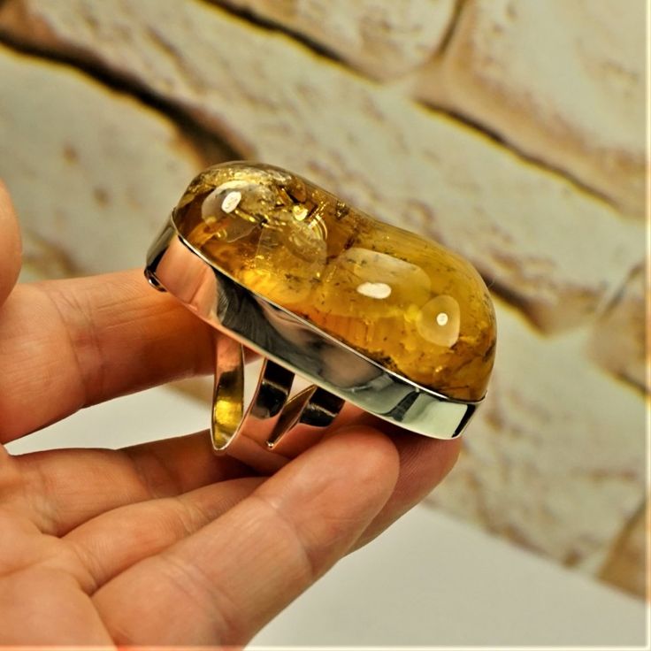 a person holding a ring with a large yellow stone in it