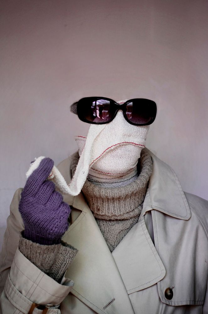 a man wearing sunglasses and a trench coat with an elephant head in the middle of his face