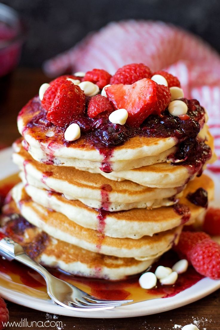 a stack of pancakes topped with strawberries and nuts