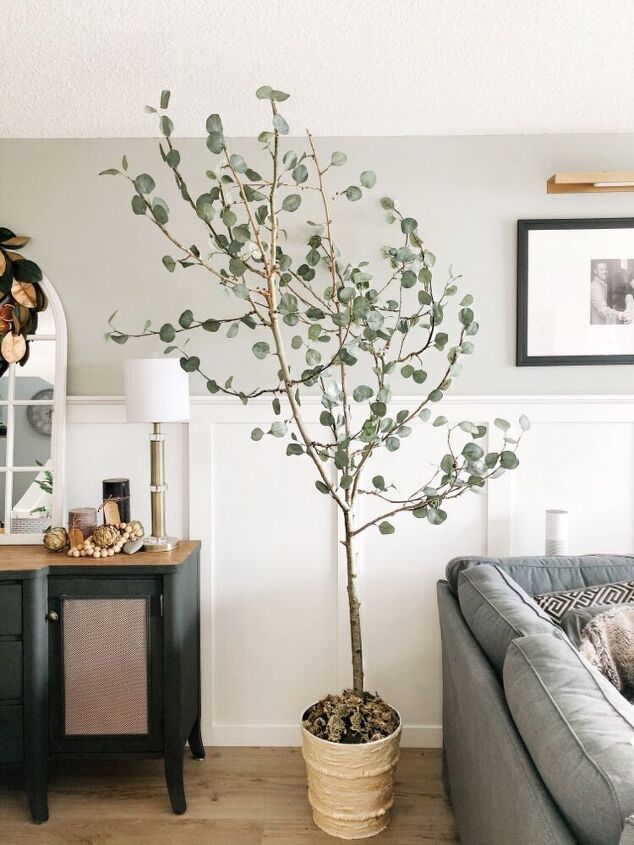 a living room with a couch and a tree in the middle of it on top of a hard wood floor