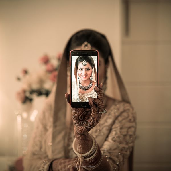 a woman taking a selfie with her phone in front of her face and wearing a bridal outfit