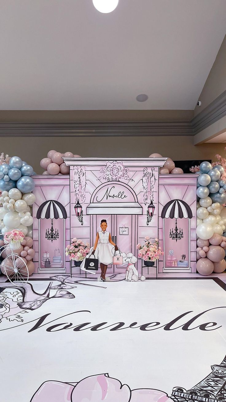 a woman is standing in front of a pink and white backdrop with balloons on it