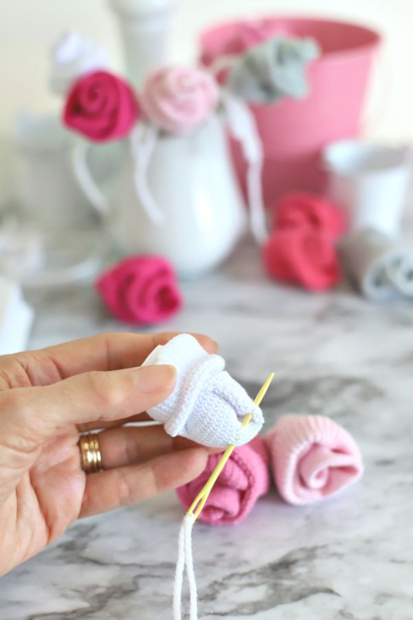 someone is knitting yarn on the table with pink and white flowers in the vases behind them