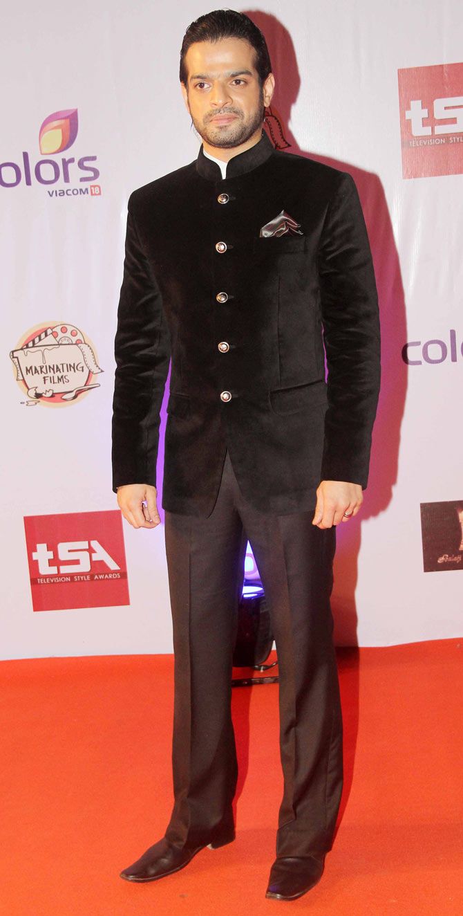 a man in a tuxedo poses on the red carpet at an awards event