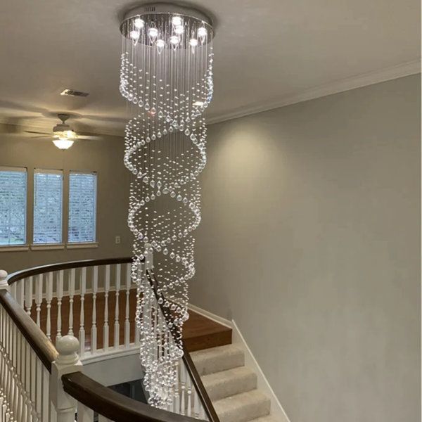 a spiral staircase with chandelier hanging from it's sides in a house