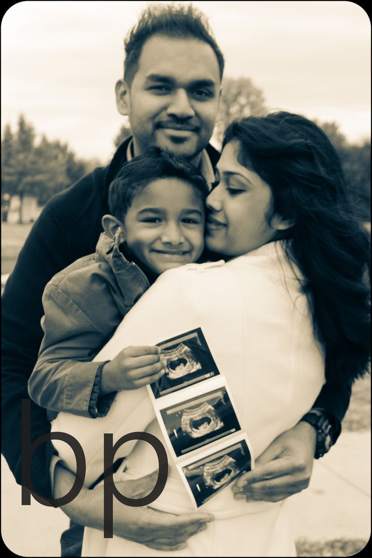 a man and woman hugging each other while holding a child