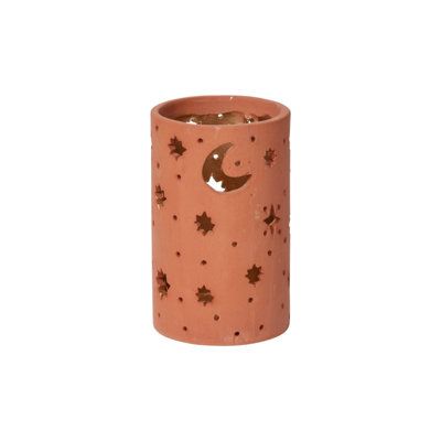 an orange candle holder with stars and moon designs on the outside, in front of a white background