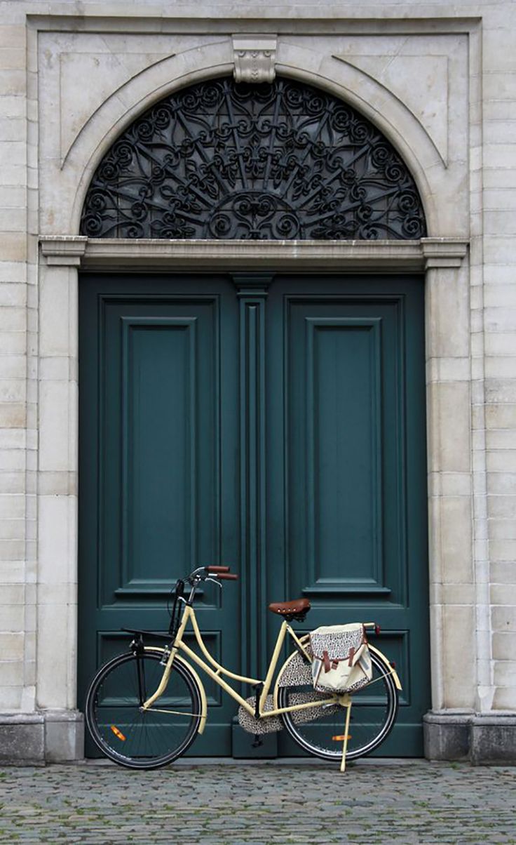 a white bicycle parked in front of a green door