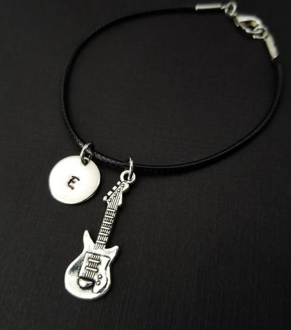 Personalized Waxed Cord Bracelet!  A detailed guitar charm on a black waxed cord makes the perfect gift for you or your best friend.The music charm is made from zinc alloy and measures 30 mm by 10 mm.  The guitar charm is reversible.  The bracelet is a waxed braided rope and measures 7.25" with a 1-2" extender (see last picture).  The lobster clasp is zinc alloy.  The black cord bracelet can be personalized with a .5" silver plated disc stamped with the initial of your choice.  Each personalized Adjustable Leather Punk Bracelet, Adjustable Punk Style Leather Bracelet, Adjustable Punk Style Bracelets As A Gift, Adjustable Punk Style Bracelet For Gift, Black Rock Style Wristband As Gift, Adjustable Punk Wristband As Gift, Adjustable Rock Style Leather Bracelet For Gift, Adjustable Metal Bracelets For Concerts, Adjustable Bracelet Jewelry For Concerts