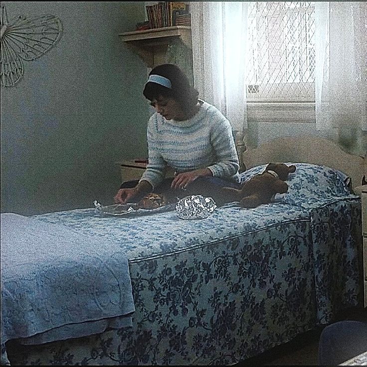 a woman sitting on top of a bed next to a dog in a blue and white room