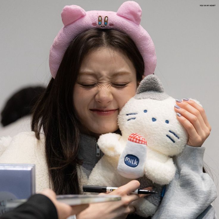 a woman holding a hello kitty stuffed animal