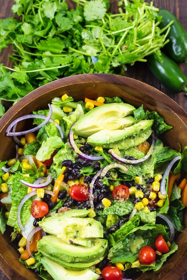 a wooden bowl filled with salad and vegetables