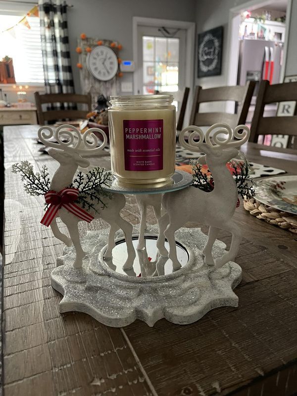 a candle is sitting on top of a reindeer sleigh that sits on a dining room table