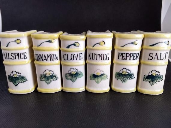 seven ceramic salt and pepper shakers with the words'cinnamon clove nutmeg salt'written on them