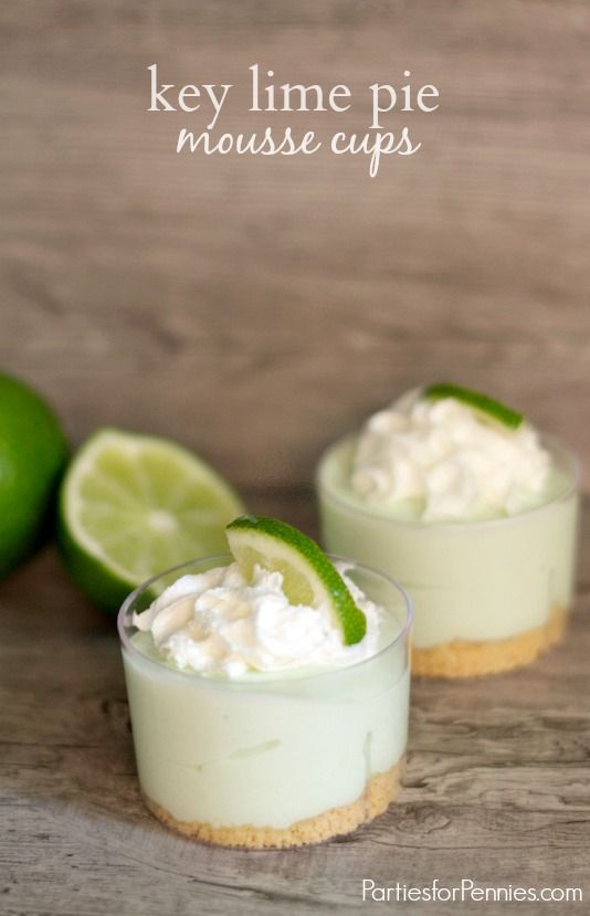 key lime pie mousse cups on a wooden table with limes in the background