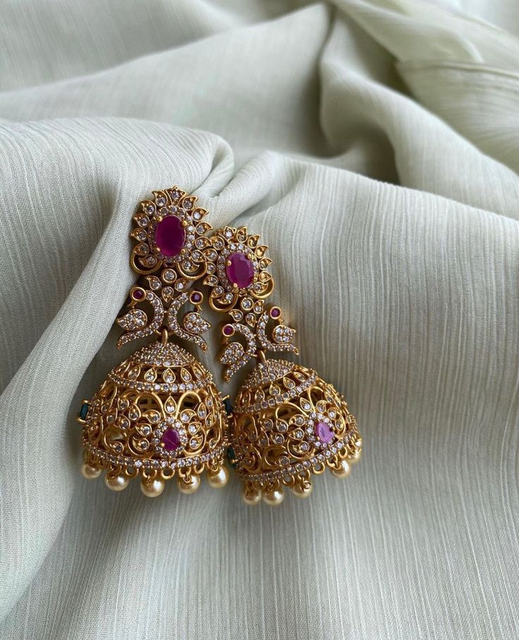 TEMPLE JHUMKA Kemp Ruby Stones Jhumka Earrings/Light weight /Antique Gold Finish/Indian Jewelry/desi jewelry / indian jhumkas Size : 3 inches approx  light weight  Elevate your style with these exquisite Temple Jhumka Earrings adorned with vibrant Kemp Ruby Stones and finished in antique gold. These Indian-inspired jhumkas are designed for both elegance and comfort, measuring approximately 3 inches in length and crafted to be delightfully lightweight. Embrace the timeless charm of desi jewelry with these stunning Indian jhumkas. Luxury Elegant Jhumkas For Reception, Luxury Intricate Design Jhumkas, Luxury Kundan Jhumkas In Temple Jewelry Style, Luxury Chandbali Jhumkas For Diwali, Luxury Traditional Jhumkas With Intricate Design, Luxury Traditional Jhumkas For Wedding, Luxury Bollywood Jhumkas With Stone Work, Luxury Drop Bridal Earrings For Diwali, Luxury Bollywood Heavy Jhumkas