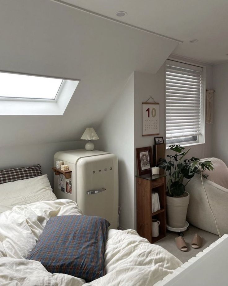 a bedroom with a bed, refrigerator and window in the corner on top of it