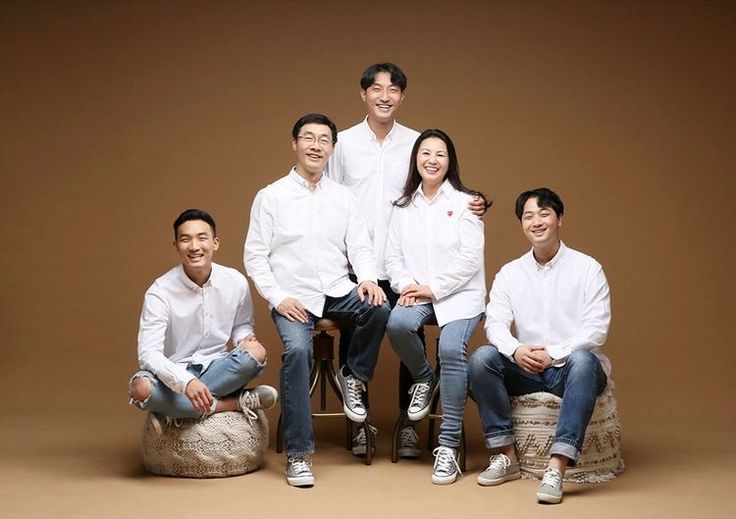 a group of people sitting on top of a wooden chair in front of a brown background