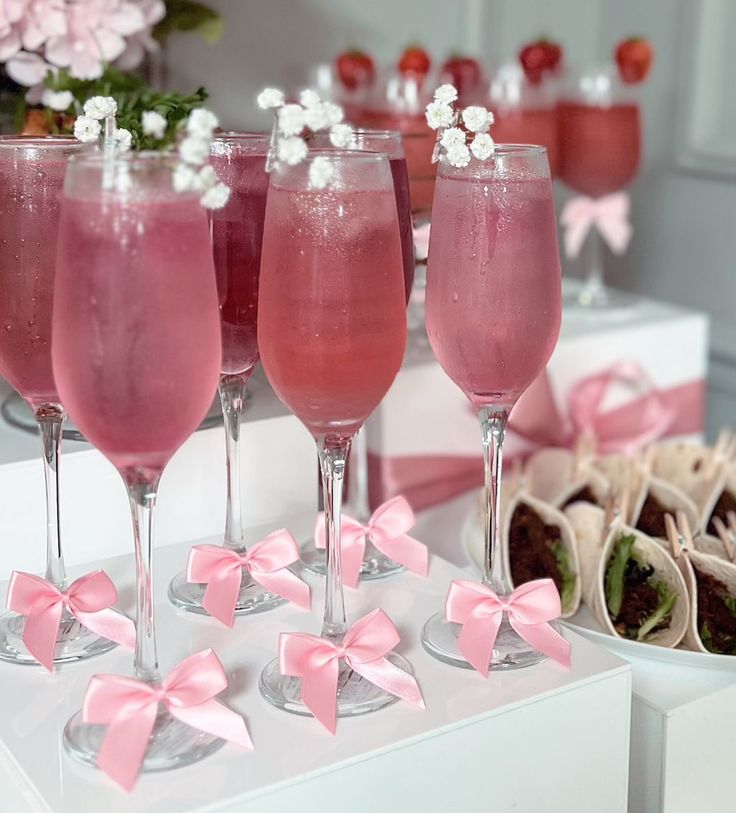 four glasses filled with pink liquid sitting on top of a table