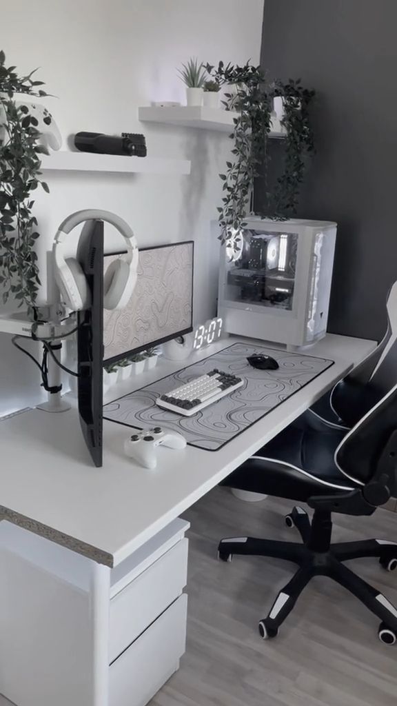 a desk with a computer monitor, keyboard and headphones on it next to a plant