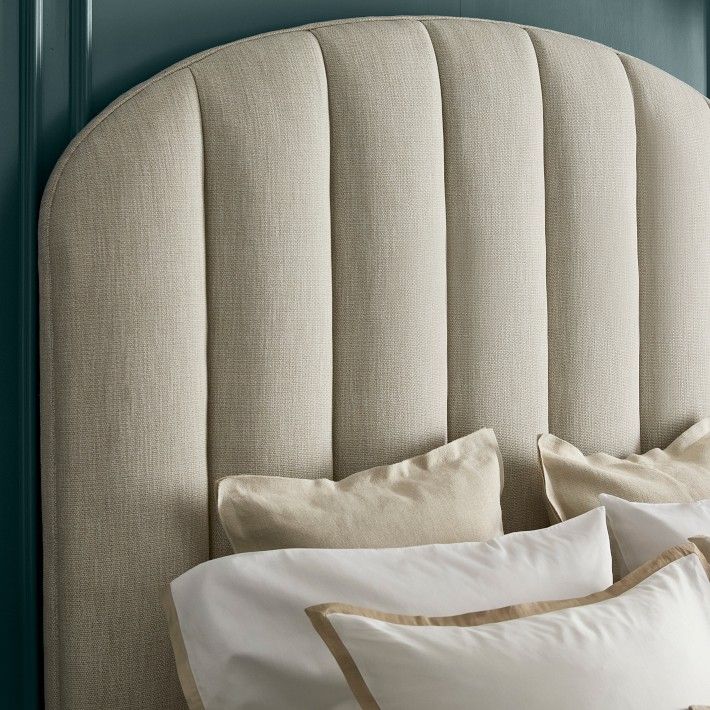 a headboard with several pillows on top of it in front of a blue wall