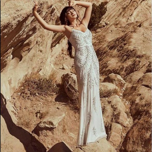 a woman in a white dress standing on rocks