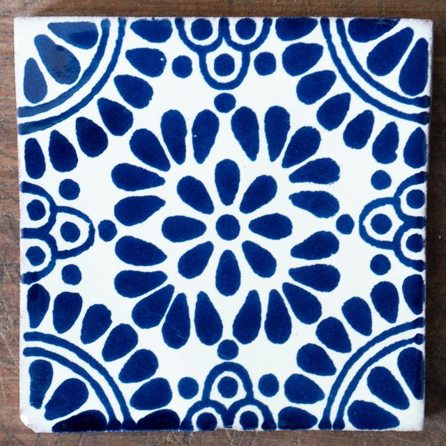 a blue and white tile with an intricate design on the bottom, sitting on a wooden surface