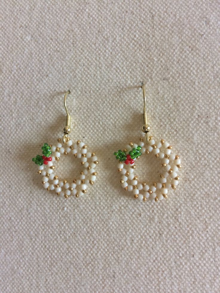 two pairs of earrings with pearls and green leaves on the bottom one is gold, the other is white