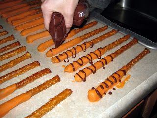 someone is decorating carrots with chocolate on a baking sheet in the kitchen,