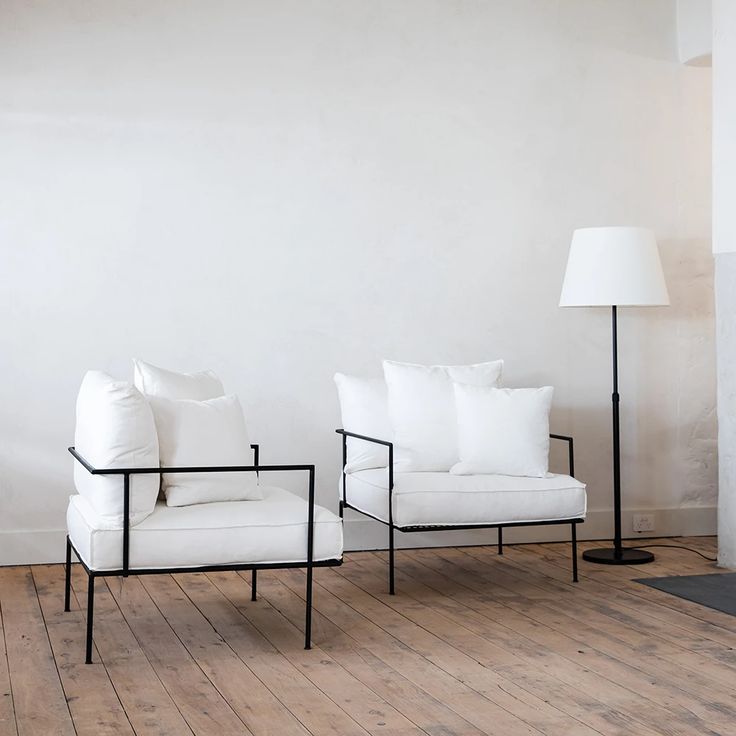 two white chairs sitting next to each other on top of a hard wood floored floor