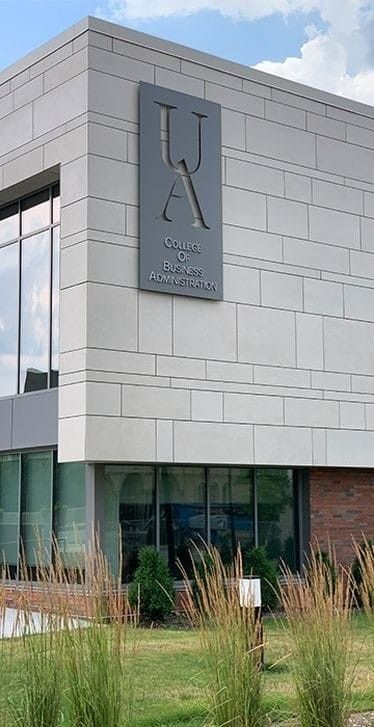 a large building with a clock on the side of it's front door and grass in front of it