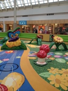 the interior of a shopping mall with flowers and plants on the ground in front of them