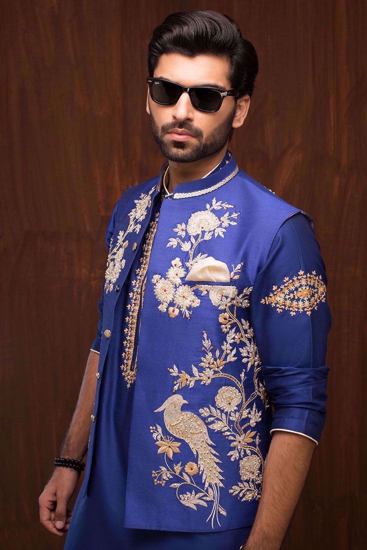 Enhance your attire with a cosmic cobalt raw silk waistcoat, complementing your kurta and pajama ensemble. Ideal for weddings, formal occasions, or religious ceremonies.The cosmic cobalt hand-embroidered raw silk waistcoat is truly enchanting, featuring meticulously crafted motifs of birds and flowers adorning the front side. The intricate embroidery in gold and silver, with a touch of maroon, adds a regal touch to the waistcoat, elevating its charm and sophistication.Paired with a matching kurt Gents Kurta Design, Gents Kurta, Birds And Flowers, Cultural Celebration, Stylish Party Dresses, Kurta Designs, Raw Silk, Formal Occasion, Gold And Silver