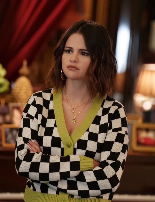 a woman standing in front of a mirror wearing a black and white checkered sweater