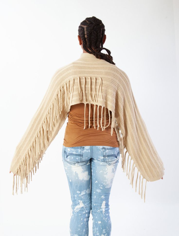 Give your look a western edge and add a wide-brimmed hat! Wear it on its own as a top or layer over a slip dress or camisole and jeans. For a breezy poncho version, see our Olympia Poncho. Oversized Mock Neck Crop Top in Multi-Ladder Stitch with Kimono Sleeves and Asymmetrical Fringe Accents. 5% WOOL, 20% NYLON, 20% ACRYLIC, 55% POLYESTER Style #G889 One Size Beige Poncho For Festival, Chic Fall Poncho For Beach, Chic Beach Poncho For Fall, Chic Fall Beach Poncho, Chic Beige Poncho For Spring, Beige Poncho For Spring Layering, Spring Festival Poncho Cape, Spring Festival Poncho, Trendy One-size Poncho For Spring