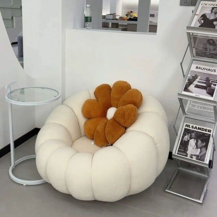 a stuffed animal sitting on top of a white chair next to a table with magazines