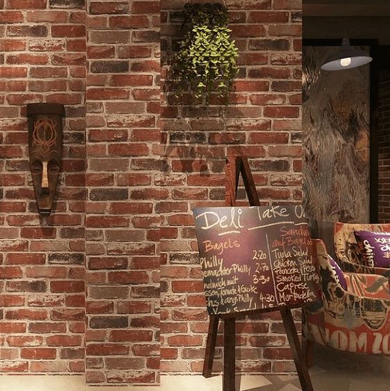 a brick wall with chalkboard menus on it and two planters hanging from the side