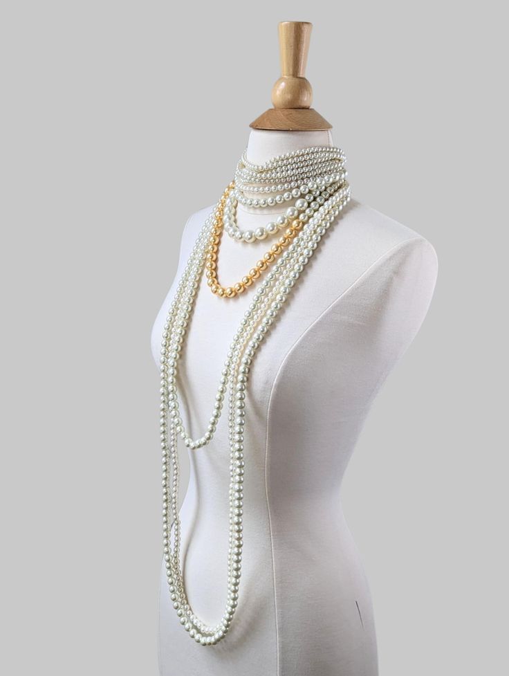 A one of a kind piece. This beautiful pearl statement necklace featuring a pearl choker with layers of long pearl strands.  Pearls are made of glass.  This necklace is a custom piece. The choker part requires an accurate measurement of the neck circumference if you would like it to sit tightly on the neck. If between sizes, please choose the shorter length. The choker is made with elastic material and the necklace comes with a 3" extender, it would be easier to adjust if it's a little tight. If the choker is loose, it won't stay on neck very well.  If it's a gift, we can make the choker part in the common length of13.5" with a 3" extender. If you would like the gold colored pearl to be a different color, please let us know, we have other color options. Thank you! Multi-strand Pearl Chain Necklace For Party, Multi-strand Pearl White Pearl Necklace For Party, Party Pearl Multi-strand Beaded Necklace, Long Single Strand Pearl Necklace For Party, Long Pearl White Pearl Necklace For Party, Party Single Strand Pearl Necklace, Long Pearl Beaded Necklace For Party, Long Pearl Necklace For Party, Long Pearl Necklace With Pearl Chain For Party