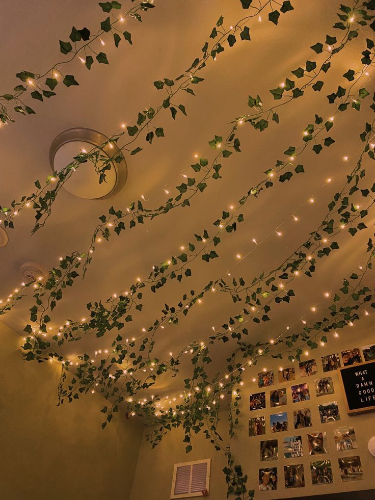 A comfy looking, aesthetic bedroom, with fairy lights and vines along the ceiling and walls. Perfect sleep room for teenagers. Vines And Twinkle Lights, Lights On Ceiling Bedroom, Vine Lights On Ceiling, Hanging Vines Lights, Vine And Lights Bedroom Decor, Vines On Slanted Ceiling, Vine Ceiling Decor, How To Put Vines On Ceiling, Ceiling Vines Decor